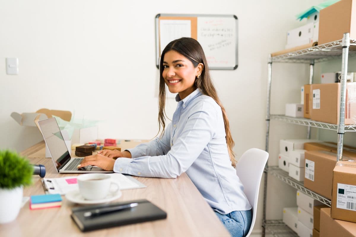 Empreendedora sorridente trabalha em um notebook no escritório da sua empresa recém-aberta