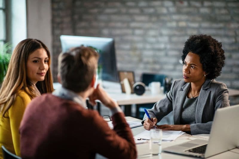 Consultor financeiro analisa relatórios em reunião com clientes no escritório