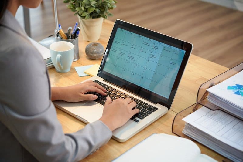 Empresária consulta o calendário e o cronograma da reforma no notebook em escritório